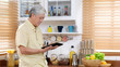 © mangpor2004 - Senior asian man using digital tablet at home background, Elderly asia male and digital tablet standing in kitchen, Active old retirement people and technology lifestyles