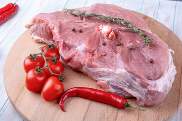 Wall Mural - piece of pork meat, cherry tomatoes, chilli on a round wooden cutting board