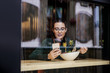 © Dusan Petkovic - Pensive young girl sitting in restaurant, having salad for lunch and using smart phone for replying messages on social media. Picture taken from outside.