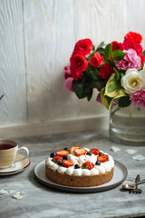Wall Mural - Side view on appetizing sweet cake with white cream and decorated with berries on the grey background with a cup of tea, vertical