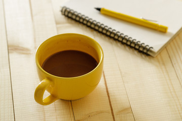 cup of hot chocolate on wooden background with notebook.  Work from home concept.