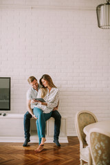 Wall Mural - Happy young couple looking at digital tablet in living room