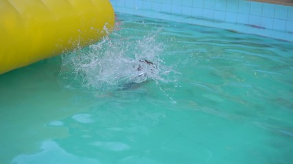 Wall Mural - Little boy on an inflatable obstacle course in an aqua park. Summer concept. Slowmotion shot