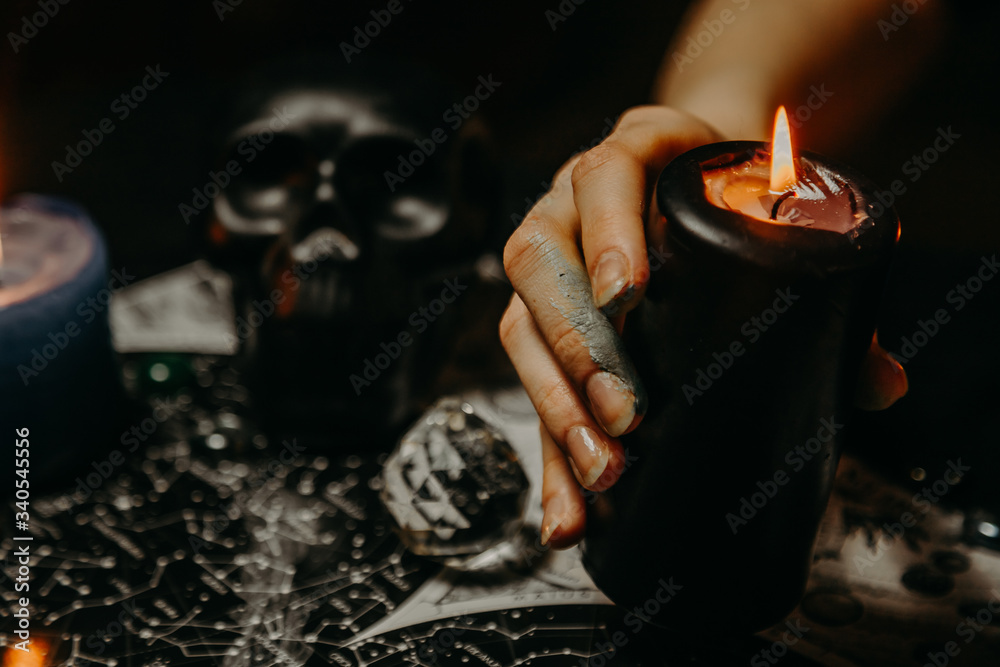 A witch performs a magic ritual with candles
 - obrazy, fototapety, plakaty 