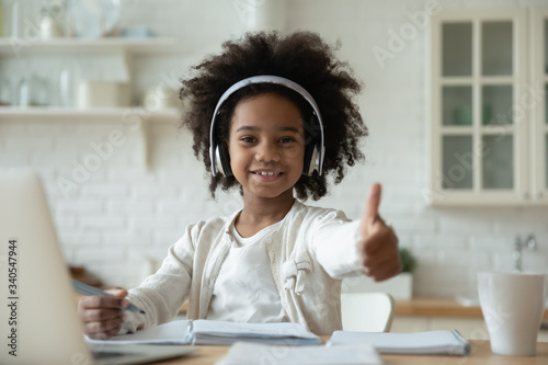 Cuadros en Lienzo Portrait of happy little African American girl pupil in headphones study online