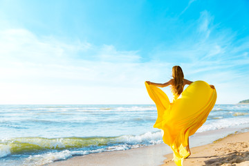 Woman on Sunny Sea Beach in Yellow Fluttering Dress, Fashion Model Back Rear View, Silk Cloth Waving on Wind