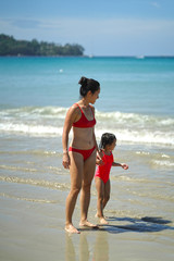 Wall Mural - Asian chinese woman spending time playing with daughter at the beach