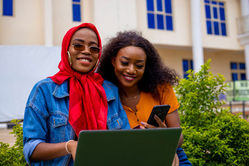 young black beautiful ladies sitting out and working on her laptop