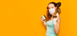 a young girl in a mask and gloves on an orange background with two cans of canned food in her hands. Funny and with ponytailsProtection AGAINST covid-19 coronavirus. Copyspace for text, banner