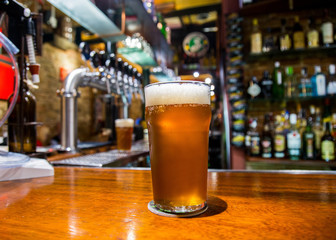 a large and fresh beer with foam on a bar