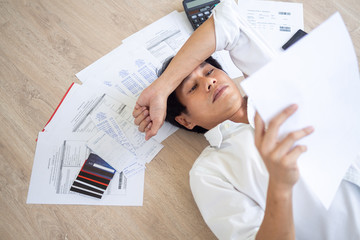 Asian men are stressed about financial problems and home expenses. With many invoices and credit card debt placed on the floor.  Financial deficit problems