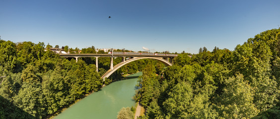 Bern, Switzerland - July 30, 2019: Railway bridge over the river. Train driving by the Bridge over Aare river in the capital of Switzerland. Super wide angle panorama