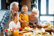 © NDABCREATIVITY - Happy grandparents with grandchildren making breakfast in kitchen