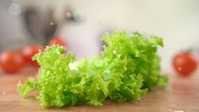 Fresh Curly Lettuce Falling Onto The Wooden Table Bouncing And Splashing Water Drops Around The Kitchen. Phantom Flex 1000fps