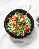 Fototapeta Kuchnia - Spaghetti with crispy ham and creamy green peas on a light background, top view