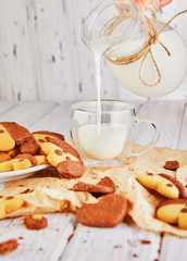 Sticker - Simple homemade shortbread cookies in the form of dogs and butterflies with a glass jug pours milk into a glass on a background of an old wooden table.