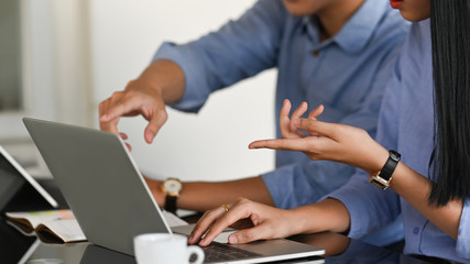 Leinwandbilder - Cropped image of business developer team working with computer laptop and tablet while sitting together at the working desk over comfortable living room as background.