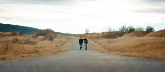 Friends with a dog hiking down the road