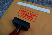 Red Handle Rubber Stamper And You've Been Served Text Isolated On The Table.