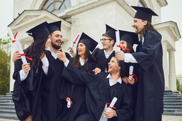 A group of graduates with scrolls in their hands are smiling