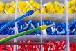 © KPixMining - Colorful insulated crimp ends of power cables or brown stripped copper wire. Crimped connector electric joins. Ferrule pin cord terminals organized in plastic grid of tool box detail. Selective focus.