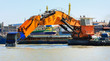 Ship with working excavator on board. Heavy machine is dredging the port