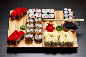 Tasty and delicious hot and cold sushi rolls on the table. Different sushi - rolls with sauce on the board of Japanese cuisine.