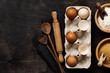 © kasia2003 - White and yellow chicken eggs and shells in an old cellulose vintage container with flour, sugar, wooden spoons and a rolling pin on an old dark wooden background.  Top view with copy space.