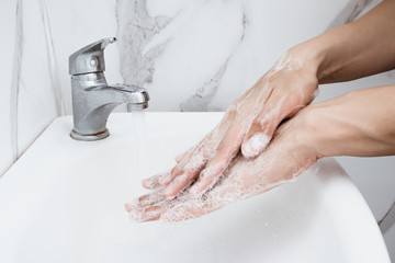 Wall Mural - Young man washing hands over sink in bathroom, closeup, Corona virus or Covid-19 prevention, hygiene to stop.