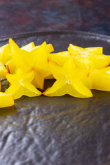 Wall Mural - Carambola on a dark background. Sliced carambola on a black background. Slices of star fruit