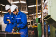 © Shutter B - Group of technician industrial engineers wearing safety uniform and safety helmet cutting metal part using hand angle grinder machine. Large industrial factory background.