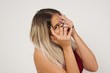 © Jihan - Anxiety - a conceptual image of a beautiful young caucasian woman covering her face with her hands and peering out with one eye between her fingers standing indoors. Scared from something or someone.