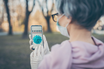 Senior woman using Coronavirus tracking app on her phone