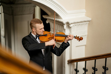 talented professional caucasian male violinist play in the hall, practice before performance. classical music concept. man in suit perform music using violin