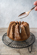 Decorative Gingerbread Bundt Cake With Sugar Glaze Being Drizzled Over Sides With Spoon