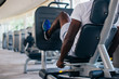 © twinsterphoto - Back view of African American man doing exercise on leg press during fitness training in modern gym.