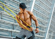 © Romario Ien - Athletic man performs exercises using resistance band. Photo of strong man training in the city. Strength and motivation