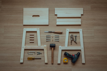 Top view of furniture assembly parts and wood work tools on wooden floor for DIY do it yourself