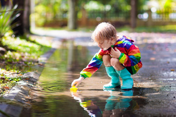 Wall Mural - Kids in puddle in autumn rain. Waterproof wear