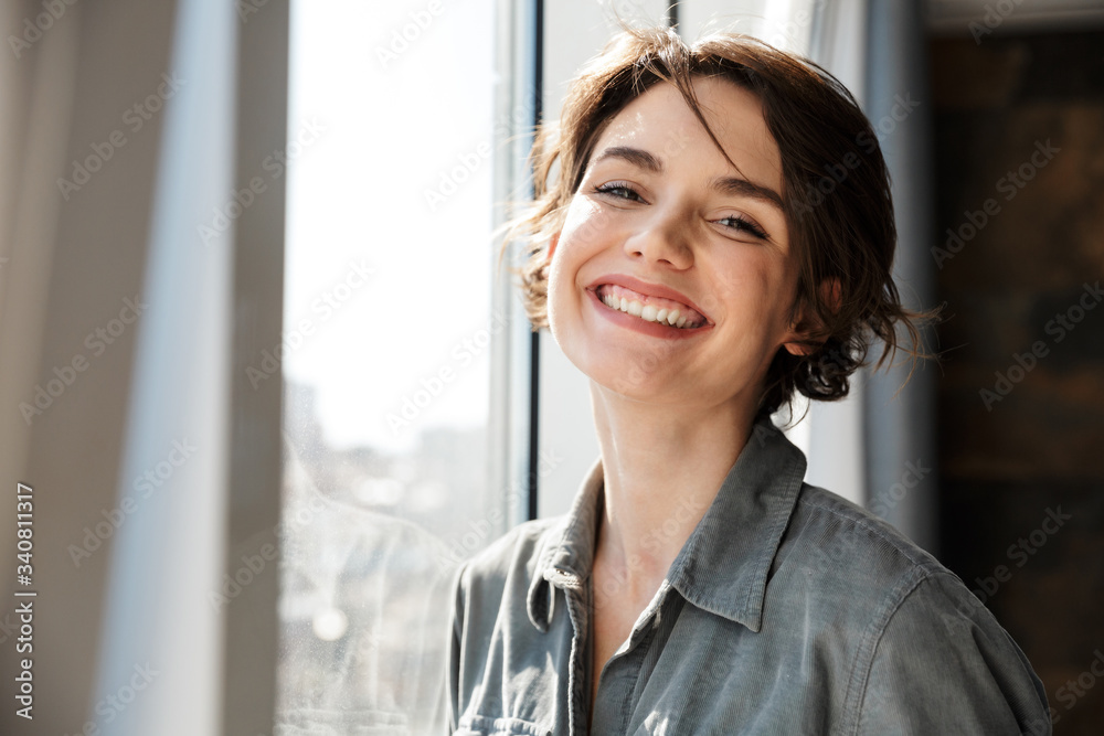 Image of beautiful young joyful woman smiling and looking at camera - obrazy, fototapety, plakaty 