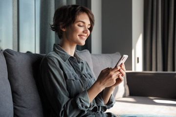 Sticker - Image of beautiful young joyful woman using mobile phone and smiling