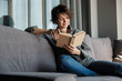 © Drobot Dean - Image of brunette cute focused woman reading book and smiling