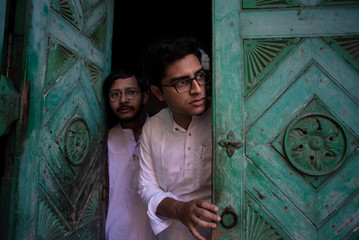 Young Indian Bengali detective and his colleague with traditional wear entering an old house. Indian lifestyle.