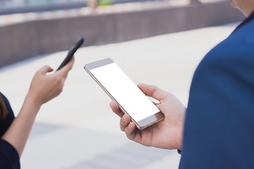 Closeup business man holding smartphone with white screen in the modern city. Business and finance concept.