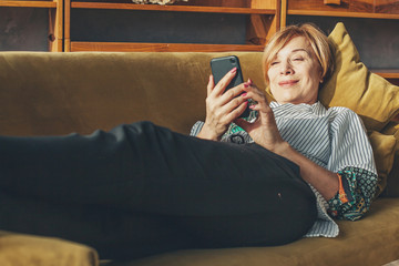 Wall Mural - Senior lady with smart phone resting at home