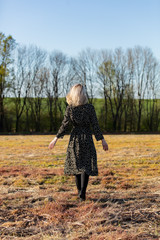 Wall Mural - Blonde girl walking in countryside in sunset time