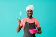 © Carlos David - Portrait of a smiling young male chef with bowl pointing up and looking at camera, against blue studio background