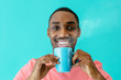 © Carlos David - Portrait of a happy young man in pink shirt enjoying his morning coffee or tea, isolated on blue