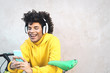 © Alessandro Biascioli - Happy Afro man using mobile smartphone outdoor - Young guy having fun listening music with wireless headphones - Youth millennial generation lifestyle and people addicted technology concept