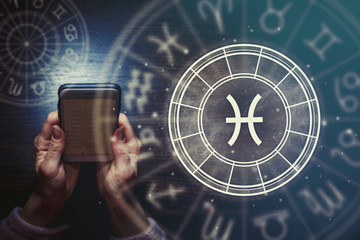 Wall Mural - female hands are holding a phone and an astrological circle with the zodiac sign pisces on a backgro